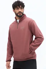 Buzo de algodón gris oscuro con cuello alto y cierre frontal parcial. Presenta un parche de marca en la manga izquierda y un logo bordado en el pecho.