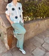 Camisa blanca con bordados de flores negras, de corte oversized y mangas cortas.