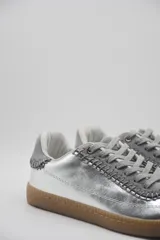 Zapatillas bajas color beige con detalles en marrón y cordones blancos.