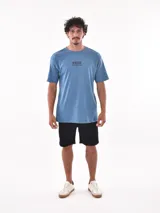 Remera negra de corte oversized con estampado circular en el pecho que incluye una palmera, una ola y la palabra 'Paradise'.