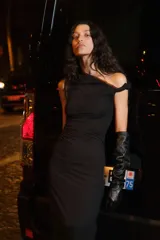 Vestido midi negro de punto elástico con escote asimétrico, manga corta con detalle girado, frunces en un hombro y en un lateral para crear un leve efecto drapeado.