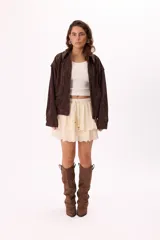 Minifalda color crema con bordado calado tipo broderie, cintura elastizada con cordón ajustable y detalle de cuentas de madera. Diseño de doble capa con volados.