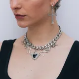 Collar plateado de cadena gruesa con dijes colgantes de cruces, espadas, corazones y un corazón alado negro.