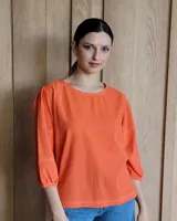 Blusa color naranja con mangas 3/4 y costuras decorativas en blanco.