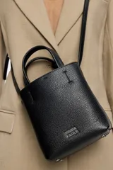 Bolso mini de piel vacuna color negro, con estructura blanda y formato vertical. Tiene doble asa corta, correa larga regulable, cierre con cinta, logo metálico BIMBA Y LOLA, acabados metálicos, bolsillo interior con cierre de cremallera e interior con logo grabado.