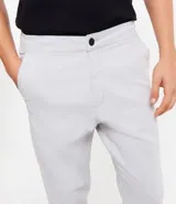 Pantalón de hombre color gris claro, corte slim, confeccionado en sarga leve. Cuenta con cierre de botón y cremallera, y bolsillos.