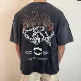 Remera negra con efecto gastado, corte boxy y estampado en la espalda con un logo abstracto en marrón, cadenas blancas, colmillos y texto "Midway Studios Buenos Aires".