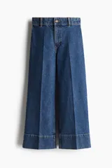 Jeans de pierna ancha en denim de algodón con leve stretch, tiro alto, corte holgado de muslo a bajo, largo cropped y bolsillos de parche atrás.