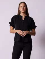 Blusa negra de gasa con cuello a la base y escote en V. Mangas cortas con elástico fruncido y espalda con elástico fruncido. Marca Floral & Ivy.