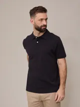 Chomba negra de piqué de algodón, corte clásico, con cuello y mangas acanalados y tapeta con dos botones blancos. Logo bordado en el pecho.
