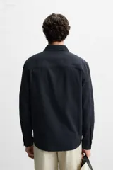 Camisa azul marino de corte regular fit, confeccionada en tejido de algodón con estructura. Tiene cuello solapa, manga larga con puños abotonados y cierre frontal con botones.