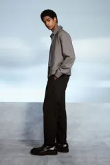 Pantalón negro de corte relajado, con cintura elástica ajustable con cordón, cierre con botón y corchete, bolsillos laterales y traseros.