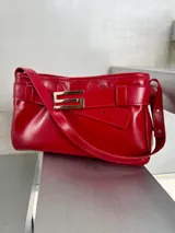 Cartera de cuero rojo con aplique metálico plateado con forma de S.