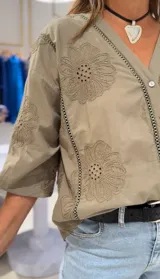 Camisa color verde militar con bordados florales, de manga 3/4 con puños elásticos y cierre frontal con botones.