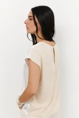 Blusa de manga 3/4 y cuello redondo, confeccionada en lino con acabado metalizado en tono beige o dorado claro.