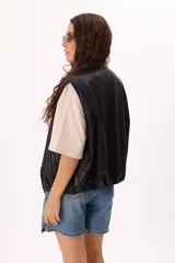 Chaleco negro de símil cuero suave con botones a presión y ruedo regulable.