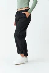 Pantalón negro de tiro medio, corte recto cropped y bolsillos laterales.