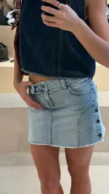 Minifalda de jean celeste con botones metálicos en el lateral y ruedo desflecado.