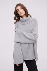Sweater gris de tejido de punto grueso, con cuello alto y mangas largas acampanadas.