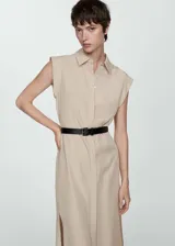 Vestido camisero midi color beige, sin mangas, con cuello camisero, cinturón negro y aberturas laterales.