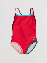 Traje de baño entero rojo con tirantes finos y espalda cruzada. Presenta un parche bordado con un monstruo en la parte inferior. Tiene ribetes en color borgoña y celeste en la parte superior, y ribetes en color naranja y verde en la parte inferior.