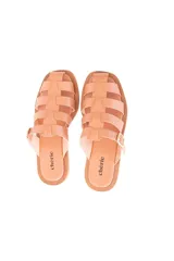 Sandalia plana color nude de cuero vacuno con tiras entrelazadas y hebilla lateral metálica.