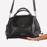 Cartera bandolera negra de cuero sintético con textura croco en la solapa superior. Tiene doble asa corta y correa larga extraíble y ajustable. El logo de la marca está grabado en una placa metálica plateada en el frente.