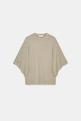 Camiseta blanca de manga corta con corte oversize y cuello redondo. El diseño presenta mangas amplias tipo capa que caen desde el hombro.