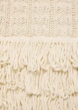 Top tejido de punto color crudo, con cuello halter y detalle de flecos en el ruedo.