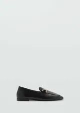 Mocasines negros de cuero con punta almendrada y detalle de hebilla dorada.