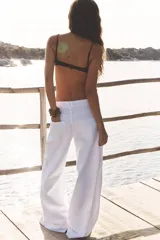 Pantalón de jean blanco, de tiro medio y corte wide leg, con cinco bolsillos y costuras laterales marcadas.