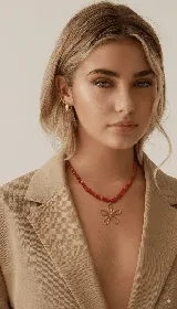 Collar corto de cuentas rojas con dije de flor dorada.