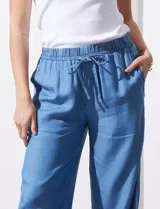 Pantalón celeste de lyocell, corte ancho, con cintura elastizada ajustable con cordón y ruedo desflecado con tajos laterales.