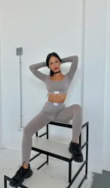 Conjunto deportivo color visón compuesto por un top corto de mangas largas con escote cuadrado y calzas largas ajustadas.