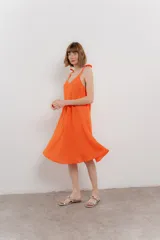 Vestido corto amarillo de lino, con escote en V y tirantes finos con detalle de moño en los hombros.