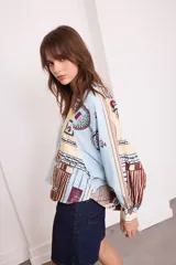 Camisa celeste con estampado de objetos y flores en tonos pastel, de manga larga y cuello en V con cierre de botones tipo alamar.