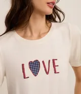 Pijama femenino compuesto por una remera de manga corta color blanco crudo con la palabra "LOVE" estampada en el frente (la letra 'O' es un corazón a cuadros azul y blanco) y un short a cuadros vichy azul y blanco con terminación de encaje negro.