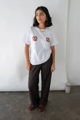 Pantalón sastrero de vestir color chocolate con finas rayas verticales blancas, de tiro alto y corte recto. Cuenta con bolsillos laterales y pretina trasera elastizada.