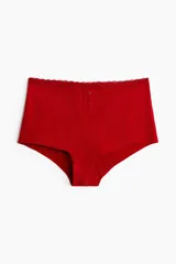 Bombacha de tiro alto color rojo, confeccionada en punto pointelle de algodón con ribete de encaje, tapeta de botones decorativa y piernas de corte bajo.