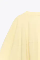 Camiseta color amarillo pastel de corte amplio, cuello redondo y mangas cortas.