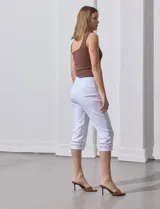 Pantalón capri blanco de gabardina elastizada con bolsillos simulados, pretina ancha, corte recto y detalle de puntilla en el ruedo.
