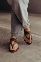 Sandalias marrones de cuero con tiras, microtachas doradas y hebilla lateral.