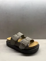 Sandalias grises con dos tiras anchas con hebillas plateadas, plantilla de corcho y suela de goma negra con plataforma.