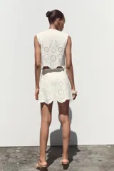 Falda pantalón corta de tiro alto color blanco con bordados florales perforados y forro interior. Cierre lateral con cremallera oculta.