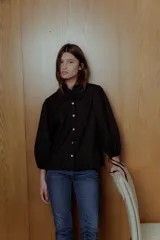 Blusa negra con cuello bebé con volados, mangas 3/4 abullonadas con lazo y botones blancos.