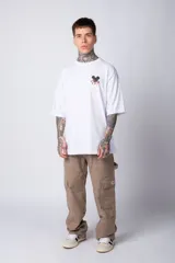 Remera blanca de algodón de corte oversize con mangas cortas y cuello redondo. Presenta un pequeño estampado en el frente con la figura de Mickey Mouse y caracteres orientales.
