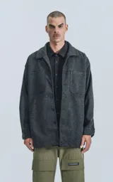 Chaqueta gris de paño con cuello clásico, cierre frontal con botones a presión, bolsillos frontales y corte recto.