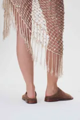 Sandalias bajas de cuero color beige con detalle de tachas metálicas en la tira delantera.