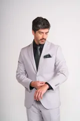 Traje de vestir gris claro, compuesto por saco de dos botones con solapa de muesca, bolsillo de ojal y dos bolsillos de parche. Incluye pantalón de vestir a juego.