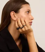 Set de tres anillos dorados con detalles esmaltados en negro. Incluye un anillo con diseño circular, otro con forma de lágrima y un tercero liso.